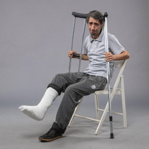 Man with an Injured Leg Sitting Down Holding Crutches